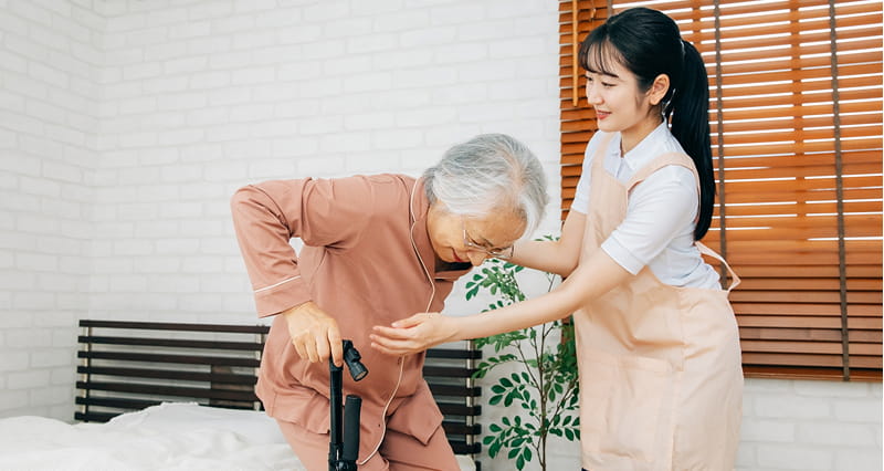 車椅子に座った高齢の女性が、介護士と楽しそうに会話をしている